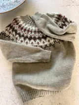 Sweater tejido a mano de corte clásico, color gris con diseño de guarda nórdica en el canesú en tonos blanco, marrón y detalles en rojo.