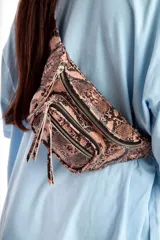 Riñonera con estampado de piel de serpiente en tonos marrones y negros. Tiene tres compartimentos con cierre de cremallera y correa ajustable.