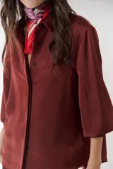 Camisa azul marino de satén con cuello clásico, cierre frontal con botones y mangas largas con puños abotonados.