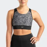 Top deportivo Reebok Running Aop, con estampado gráfico abstracto en tonos grises y negros. Presenta escote redondo, tirantes anchos negros y banda elástica inferior negra con logo Reebok en blanco.