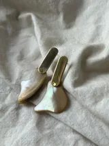 Par de caravanas colgantes con piezas irregulares de nácar y detalles en metal dorado.