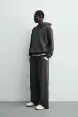 Pantalón jogger de corte wide fit confeccionado en tejido fluido con viscosa. Presenta un efecto lavado, cintura elástica ajustable con cordón, pliegues frontales, bolsillos laterales y un bolsillo trasero de plastrón.