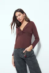 Top de manga larga color negro con escote en V y detalle de frunce central. Presenta un corte entallado que se adapta a la figura.