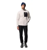 Campera polar de corderito en color beige, con cuello alto, cierre frontal completo y un bolsillo en el pecho de color negro con cierre y etiqueta de la marca. Cuenta con bolsillos laterales y puños con ribete elástico.