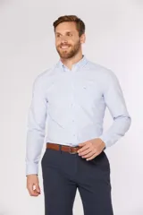 Camisa de manga larga con diseño de rayas finas en color celeste, cuello con botones y bolsillo ojal en el pecho.