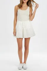 Falda corta de viscosa y algodón color blanco, con cintura elástica con cordón ajustable y diseño de volados escalonados.