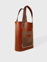 Matera de cuero color marrón con bolsillo exterior con textura símil piel de cocodrilo. Interior forrado con compartimento para el mate y bolsillo de cuero.