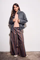 Pantalón de jean tiro medio, corte wide leg, confeccionado en tela de algodón con rayas verticales marrones y azules.