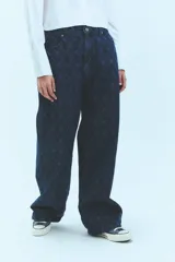 Pantalón de jean azul denim con tiro bajo, corte oversize y grabado láser con monograma.
