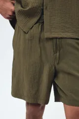 Pantalón corto de tejido texturizado verde militar, con corte relajado, cintura elástica con cordón de ajuste y bolsillos laterales.