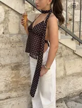 Top marrón con estampado de lunares blancos, escote halter y tiras finas. Incluye una tira de tela que se ata al cuello.