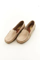 Mocasines de cuero vacuno color beige con acabado mate, costuras visibles artesanales en el empeine y suela de perfil bajo.