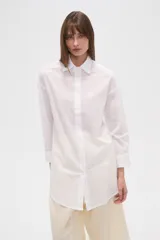 Camisa marrón holgada de algodón con cuello clásico, cierre frontal con botones y mangas largas con puños abotonados.