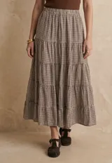 Falda larga de corte acampanado con diseño de volados horizontales y estampado de cuadros vichy en tonos marrón y blanco. Cuenta con cintura elástica para un ajuste cómodo.