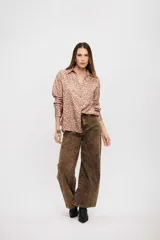 Camisa de manga larga con cuello camisero y cierre frontal de botones. Presenta un estampado de puntos irregulares en tonos tierra.