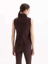 Camisa sin mangas de color marrón oscuro, confeccionada en tejido de punto, con cuello camisero clásico y cierre frontal de botones.