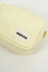 Neceser pequeño de color amarillo claro, con diseño acolchado y cierre superior blanco. Incluye una etiqueta con el logo de la marca Indian en el frente.