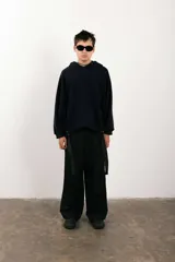 Buzo negro de corte amplio con capucha y detalle de parche circular en el pecho.