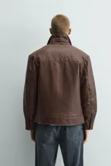 Sobrecamisa de corte relajado confeccionada en tejido efecto piel color marrón. Presenta cuello solapa, cierre frontal con cremallera, mangas largas con puños abotonados y dos bolsillos de plastrón con solapa en la parte frontal.