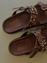 Sandalias de cuero marrón, con diseño de triple tira con hebillas, detalles de tachas y apliques de pelo con estampado animal print.