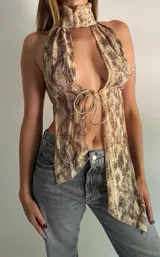 Top halter con estampado abstracto en tonos beige y marrón, con cuello alto y lazos ajustables en el frente.