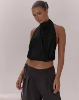 Top halter negro con cuello alto y diseño cruzado en el frente, espalda descubierta y terminación elástica en el bajo.
