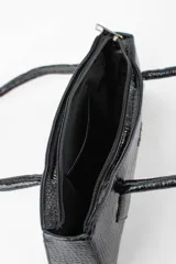 Cartera tipo baguette color negro con textura efecto cocodrilo, diseño alargado, doble asa de mano y cierre superior.