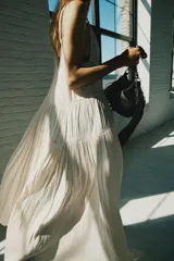 Vestido midi de satén color crudo, con escote en V, tirantes finos y detalle de lazada en el delantero.