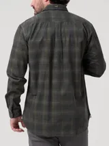 Camisa de manga larga confeccionada en algodón orgánico con textura de cotelé. Presenta un diseño de cuadros escoceses en tonos verdes y grises, cuello clásico, cierre frontal con botones y dos bolsillos frontales con solapa.