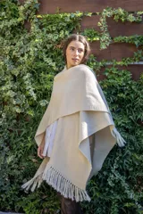 Ruana tejida a mano en punto arroz con lana merino, presenta un diseño envolvente con flecos en los extremos.
