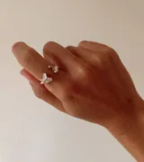 Anillo ajustable de metal dorado con diseño de mariposa, decorado con esmalte blanco y pequeños cristales brillantes.