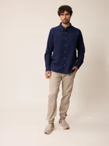 Camisa de manga larga confeccionada en algodón oxford, con cuello abotonado y cierre frontal de botones. Presenta un diseño clásico y minimalista con un pequeño logo bordado en el pecho.