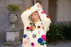 Sweater holgado de lana merino color marfil, con mangas con diseño de ochos y apliques bordados de flores en 3D de diversos colores.