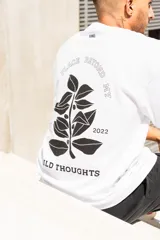 Remera blanca de algodón con estampa en la espalda que incluye texto y diseño de hojas.