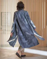 Tapado largo de lana merino afieltrada, color fucsia con diseño tie-dye artesanal en tonos claros y crudos. Tiene cuello que se prolonga a modo de cinto, aberturas laterales y bolsillos.