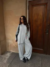 Conjunto de dos piezas color gris melange, confeccionado en tela de lanilla, compuesto por un buzo de manga larga con diseño cruzado al frente y un pantalón largo de corte holgado y tiro alto.