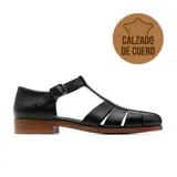 Sandalia estilo romano de cuero negro, con diseño de tiras cruzadas, talón cerrado y tira en T con hebilla metálica ajustable. Cuenta con suela plana y tacón bajo de madera.