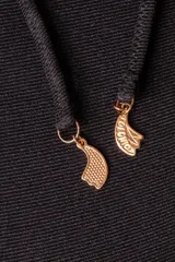 Conjunto de bikini negro brillante, compuesto por un corpiño triangular con tirantes finos y una bombacha con tiras laterales ajustables.