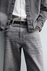 Pantalón de jeans de algodón, color gris oscuro con efecto lavado. De tiro medio y corte relajado con pierna recta desde la cadera hasta el tobillo. Presenta cinco bolsillos y cierre frontal con botonadura.