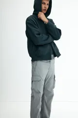 Pantalón cargo de nylon color gris claro, con cintura elástica y cordón ajustable. Presenta bolsillos laterales con cierre, bolsillos cargo con solapa en las piernas y cordón ajustable en los bajos.