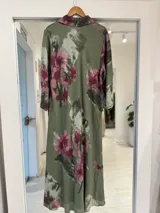 Vestido midi verde militar con estampado floral en tonos rosados y blancos, cuello camisero y cierre frontal parcial con botones.