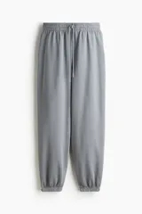 Pantalón deportivo gris de tiro alto, con cordón ajustable en la cintura elástica y bolsillos al bies. Los bajos también son elásticos y el interior es cepillado suave.
