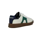 Zapatilla deportiva de hombre, estilo retro, color blanco con detalles en verde esmeralda en el lateral con borde festoneado. Posee cordones blancos y suela de goma marrón. El talón es de color azul marino.