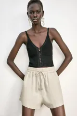 Bermuda color crema confeccionada en lino, de tiro alto con cintura elástica ajustable con cordones y bolsillos delanteros.