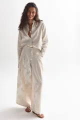 Camisa de manga larga color crema con estampado floral en relieve, cuello clásico y cierre frontal con botones.