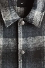 Sobrecamisa de corte relajado en tejido suave con diseño a cuadros. Presenta cuello inglés, cierre frontal con botones a presión, hombros caídos y mangas largas con puños abotonados.
