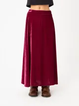 Falda larga de terciopelo color borgoña, con silueta amplia y pretina elastizada.