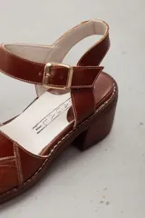 Sandalias de cuero color marrón, con faja frontal ancha con detalle de textura en relieve, plataforma sutil, taco ancho y pulsera ajustable con hebilla en el tobillo.