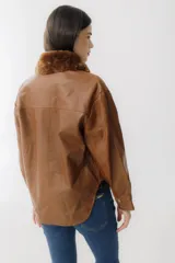 Camisa marrón de cuero sintético con cuello de piel sintética color marrón, cierre frontal con botones a presión dorados, dos bolsillos con solapa en el pecho y corte holgado.