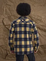 Sobrecamisa de tejido polar con estampado abstracto en tonos rojizos y azul marino. Presenta cuello clásico, cierre frontal con botones a presión, dos bolsillos frontales con solapa en el pecho y un parche decorativo.